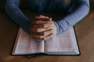 hands clasped in prayer on bible