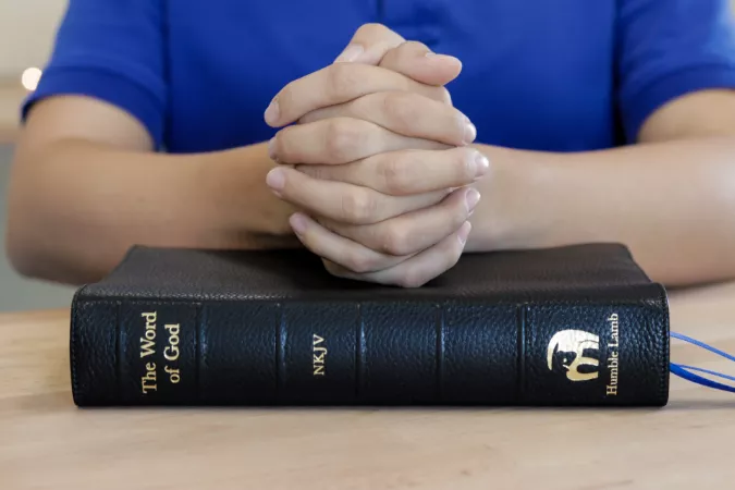 man praying with hands on bible